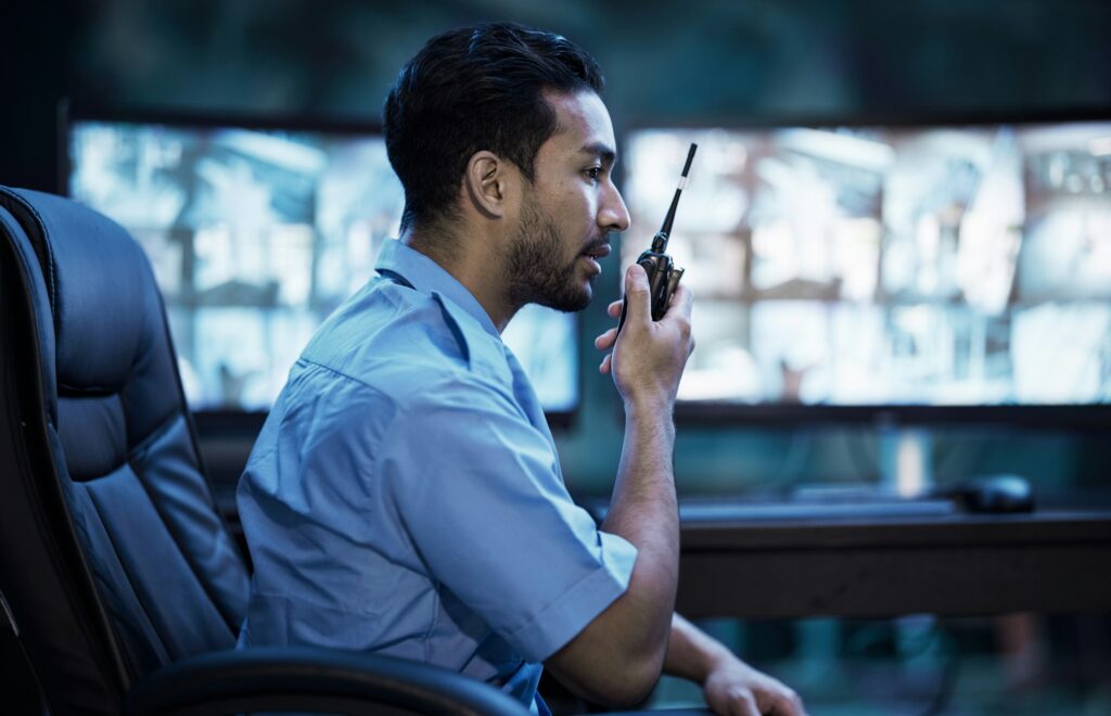 Security guard in control room, man with radio and screen to check cctv in virtual office for alarm